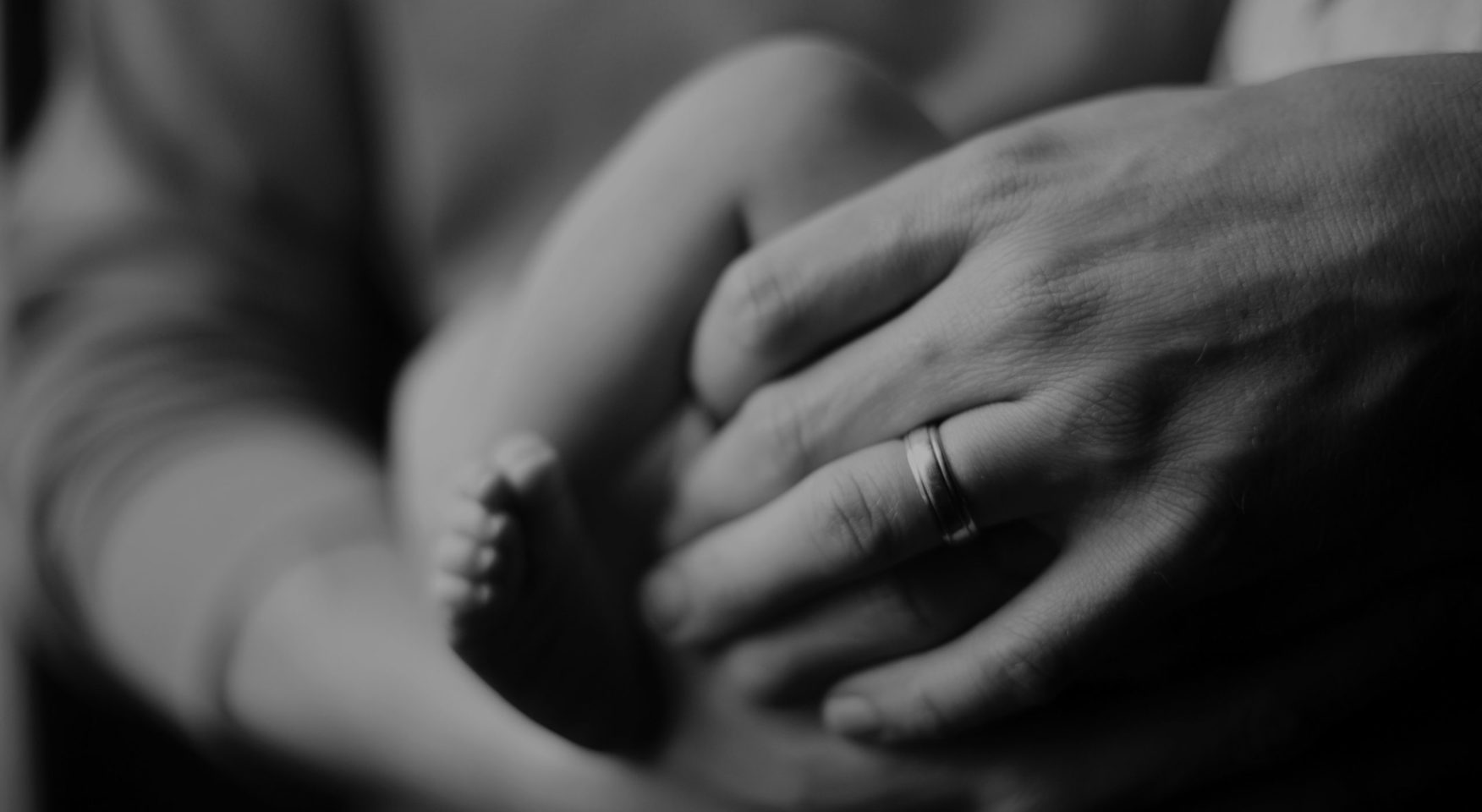 Adult holding baby closeup of hands and feet