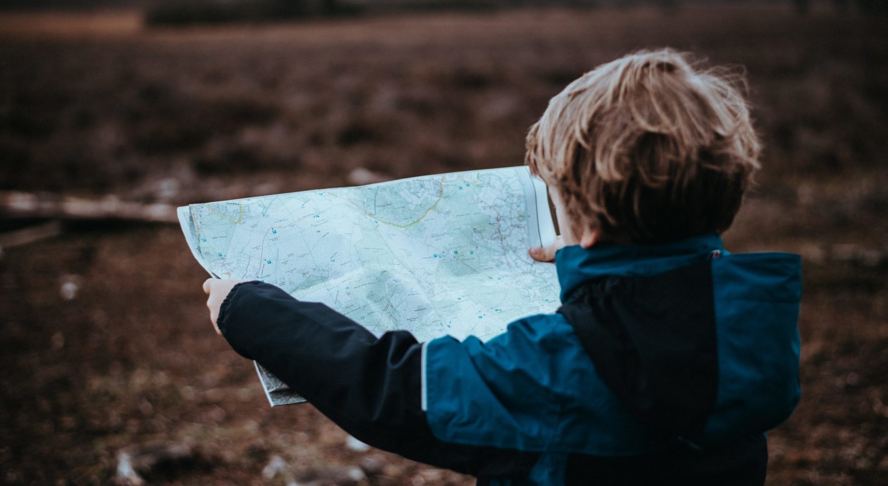 boy holding a map while standing in a field