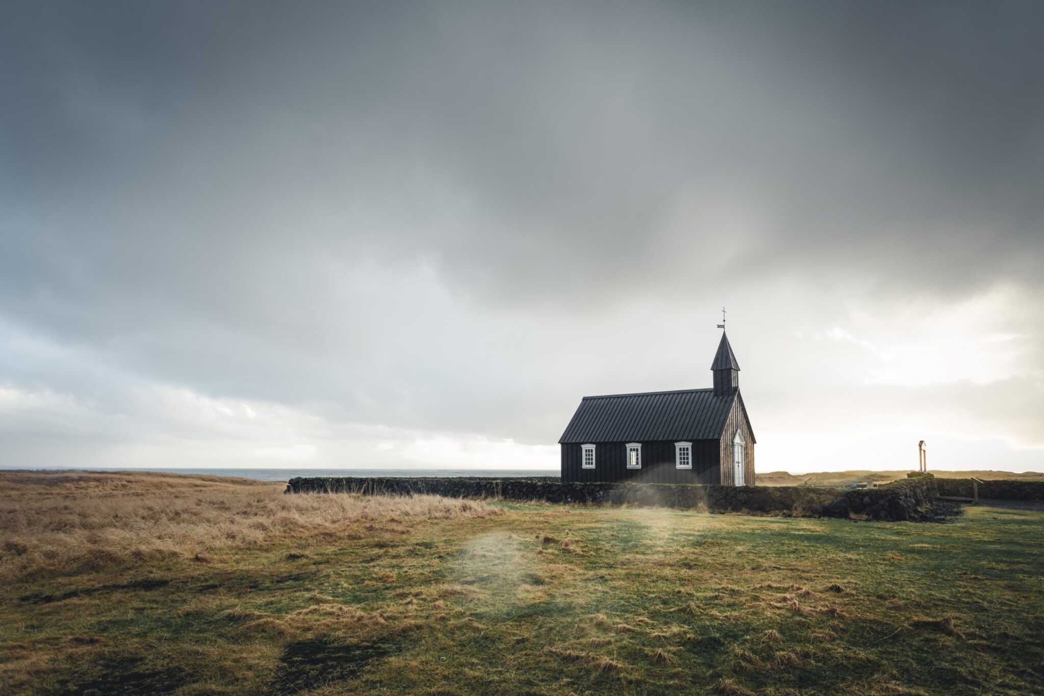 wooden church under stormy sky in a large meadow