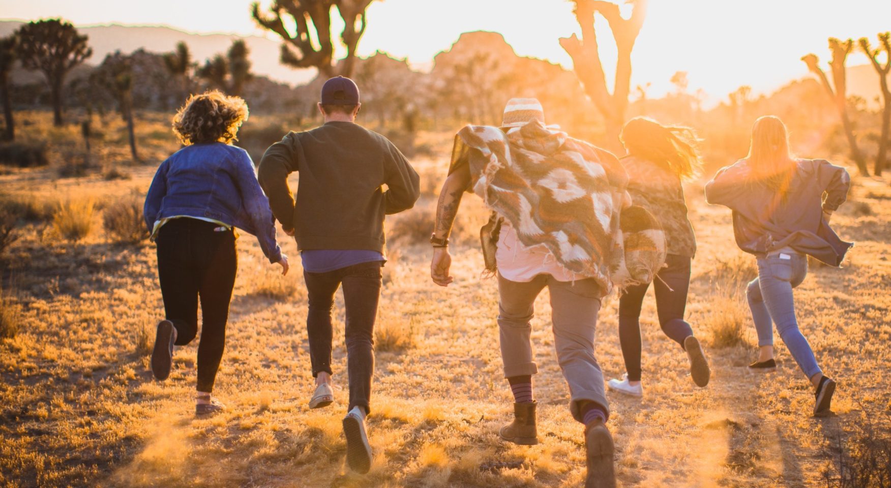 People running through the desert at sunset