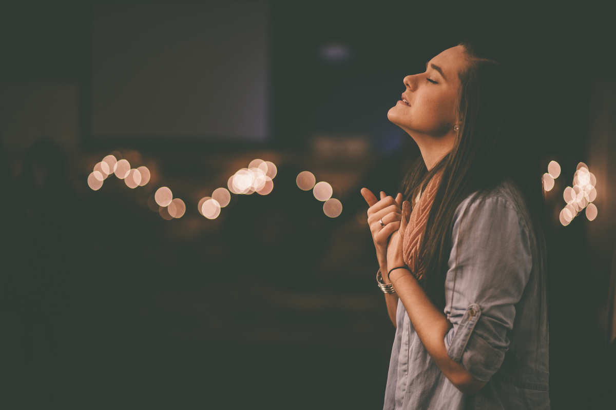 Girl worshipping in a room of twinkle lights