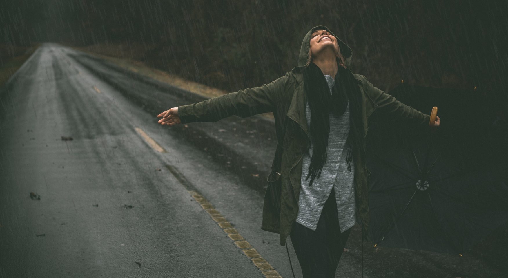 happy woman standing on rainy road