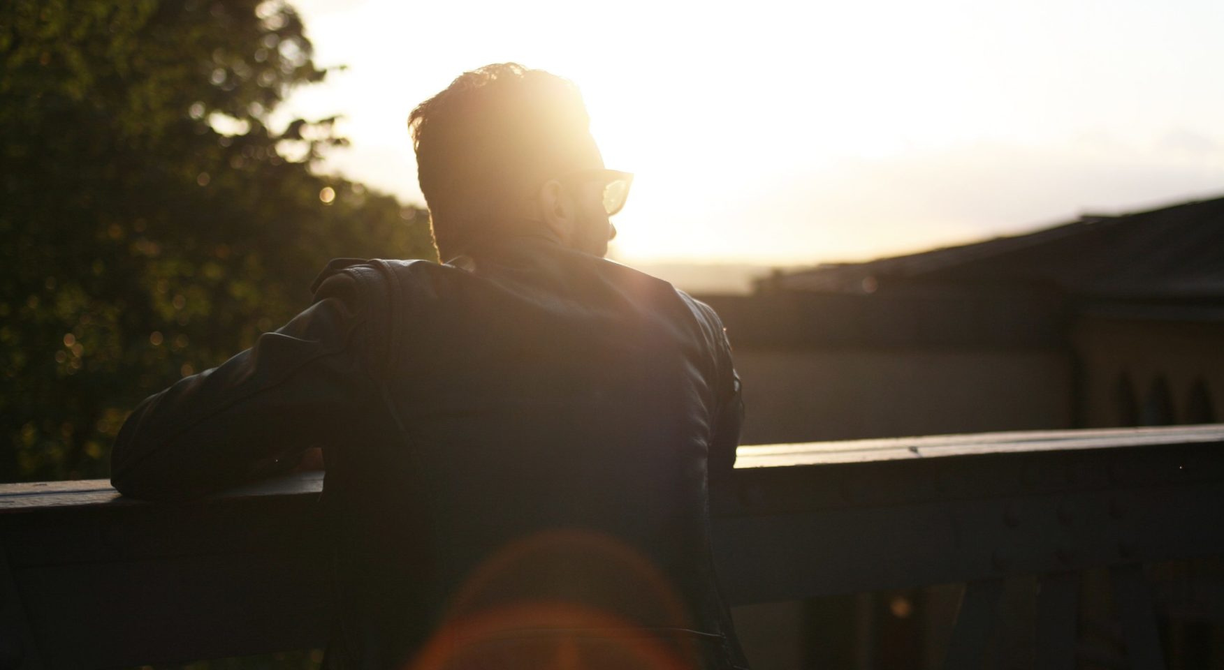 Man with sunglasses and black leather jacket staring at bright sun