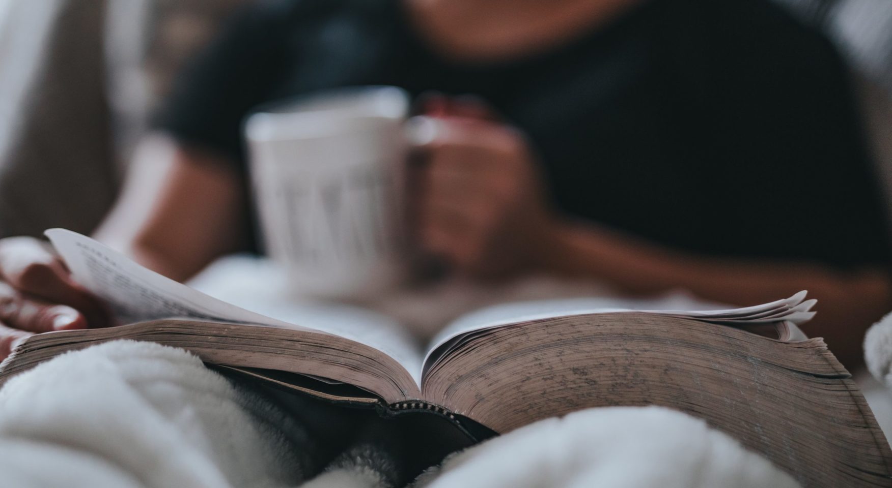 person studying bible with large white mug