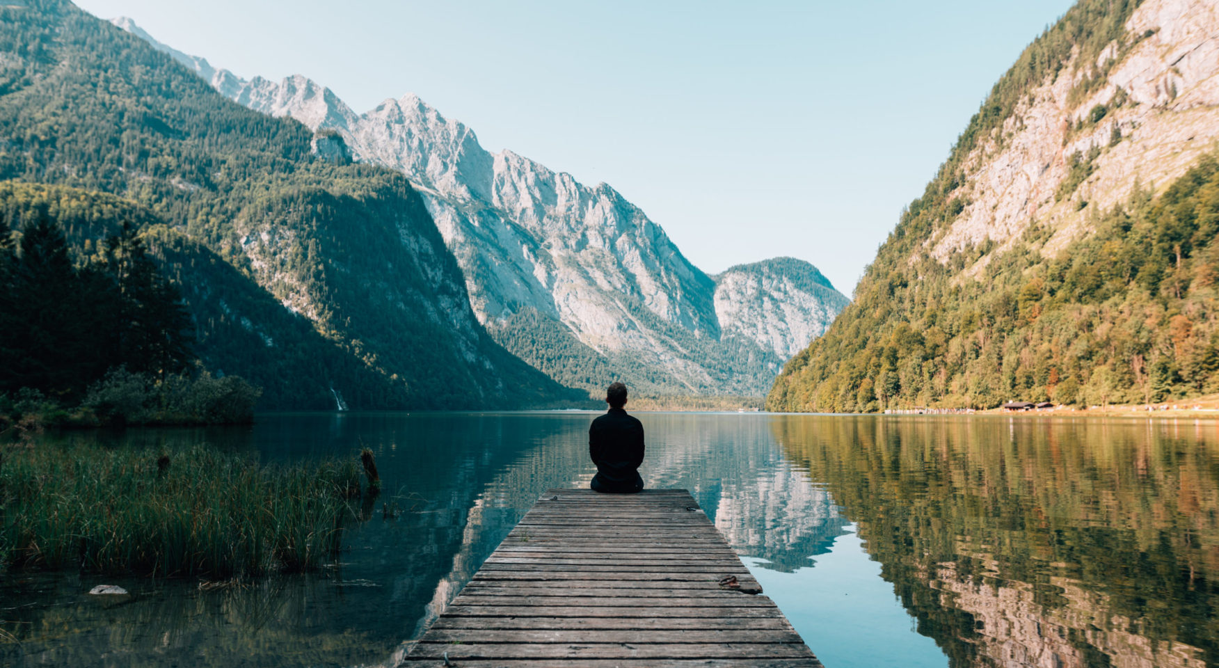 Person sitting on a dock at mountain lake