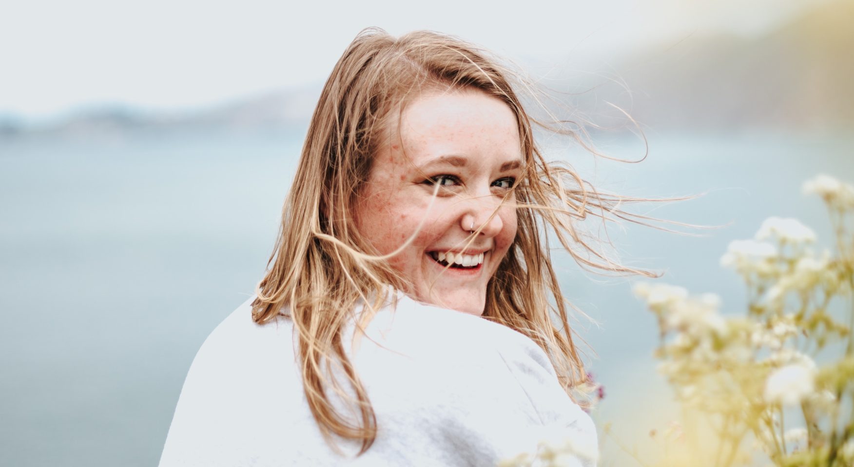 smiling woman with strawberry blonde hair on a windy day