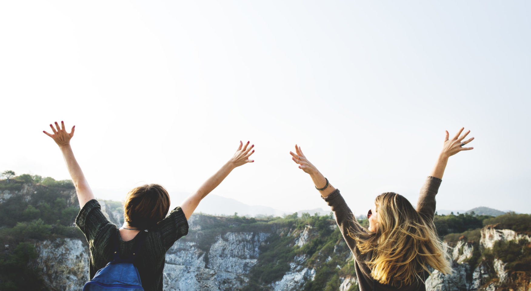 Two people worshipping at the top of a cliff