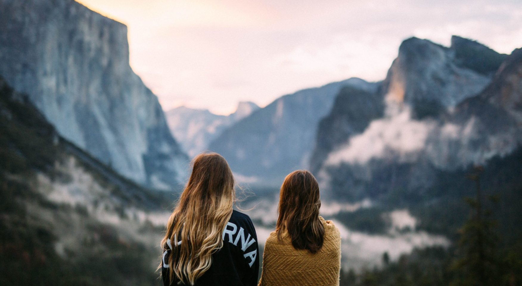 two women overlooking misty mountains