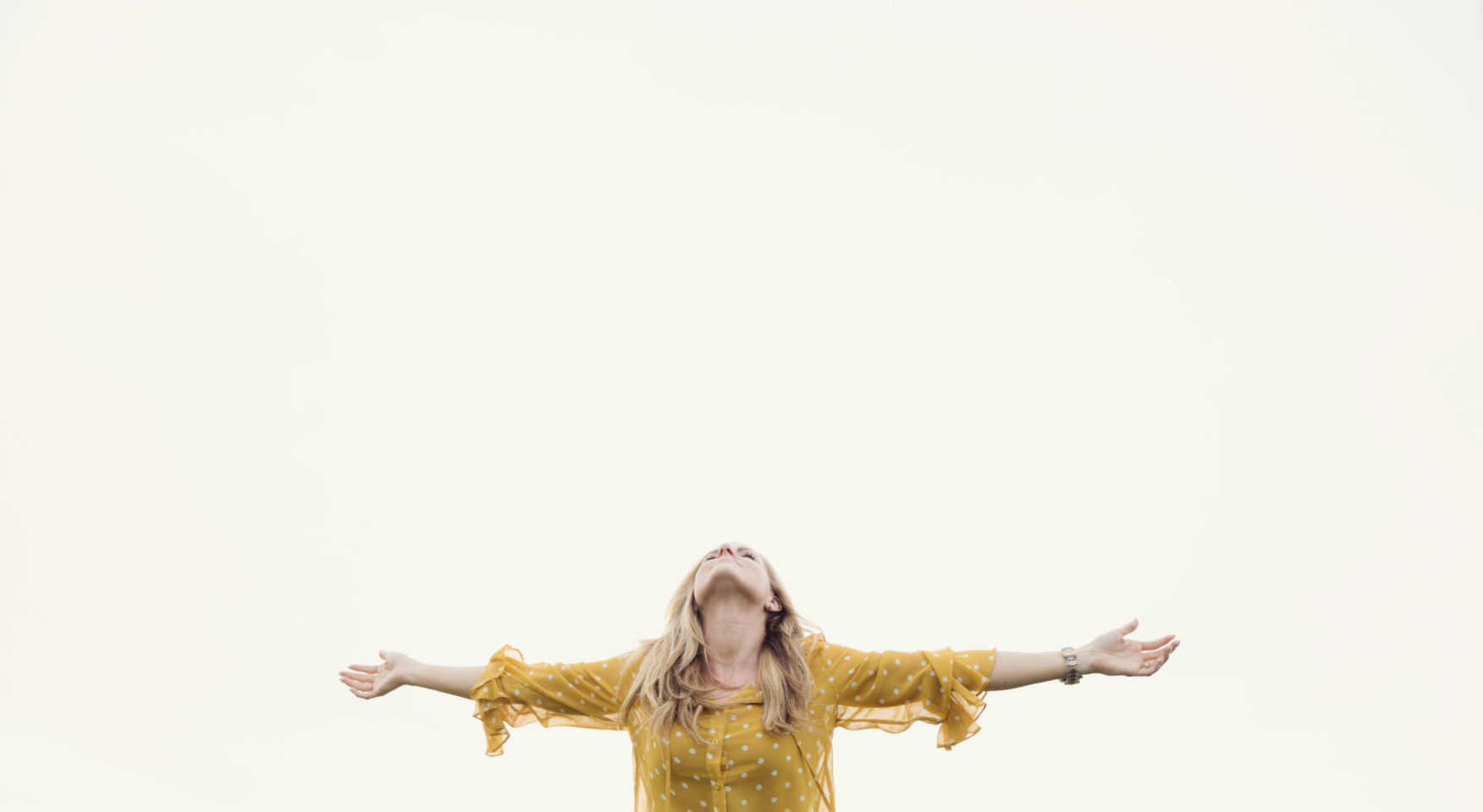 Woman in yellow shirt with open arms