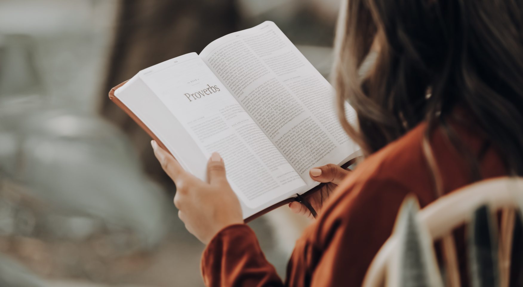 Woman in orange shirt reading Bible