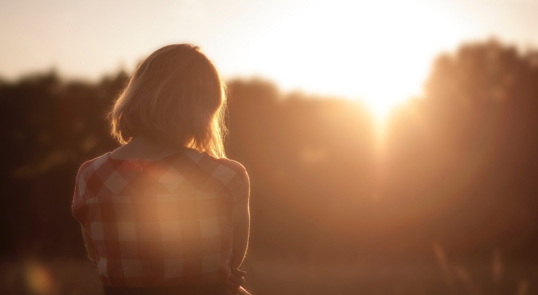 woman standing in field in golden sunlight