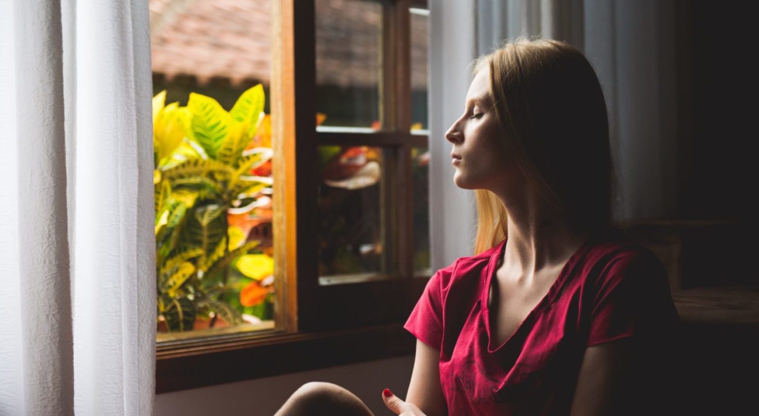 Woman in red blouse staring out of window