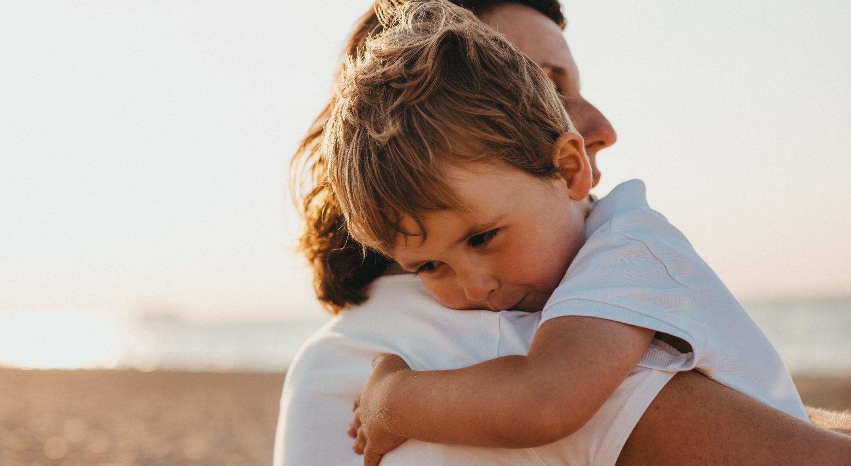 young son hugging parent on beach